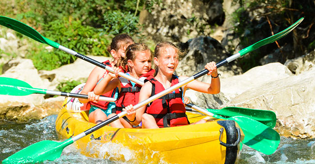 Trois enfants sur un canoë jaune descendent l'Ardèche